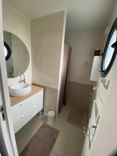 een witte badkamer met een wastafel en een spiegel bij Chambre d’hôte près de la plage bis in Pornichet