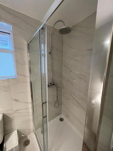 La salle de bains est pourvue d'une douche avec une porte en verre. dans l'établissement Sela House - Luton Airport, à Luton