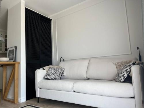 - un canapé blanc dans une chambre avec fenêtre dans l'établissement PIASKOWA ŁEBSKA OSTOJA - Local 7, à Żarnowska