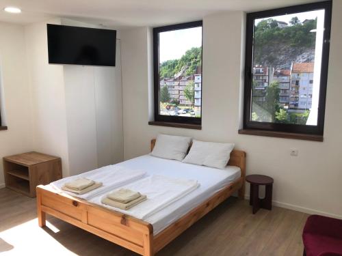a bedroom with a bed with a tv and two windows at Green River in Konjic