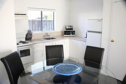 a small kitchen with a glass table and chairs at Camelot On Ulster in Hamilton