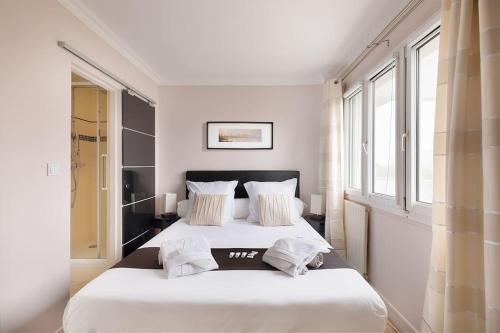 2 camas en un dormitorio con paredes y ventanas blancas en Location chic 3 chambres proche Paris & Disneyland, en Neuilly-sur-Marne