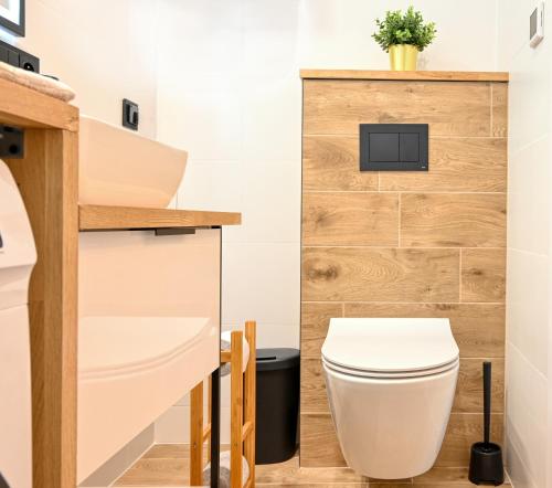 a bathroom with a white toilet and a wooden wall at Apartament Wiesental in Polanica-Zdrój