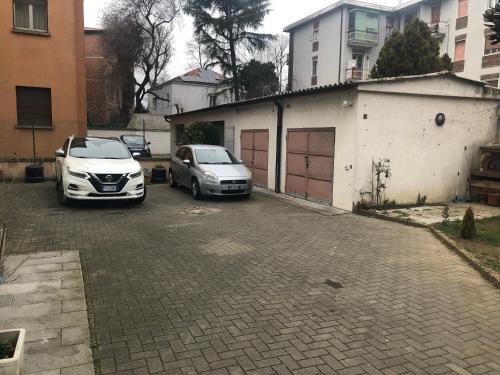 dos autos estacionados en un estacionamiento al lado de un edificio en Casa Linda, en Pavia