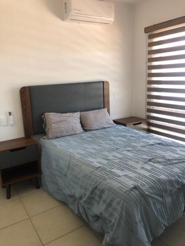 1 dormitorio con 1 cama con edredón azul y ventana en ymssjamg en Mazatlán