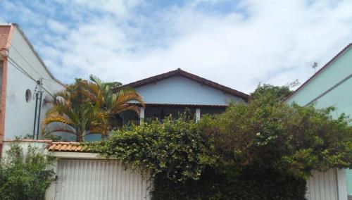 a white house with a fence and trees at Hostel Cantinho da Paz in Caxambu