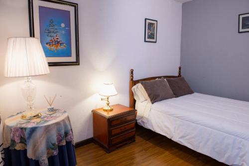 um quarto com uma cama e uma mesa com um candeeiro em Suite bien ubicada con entrada independiente em Cuenca