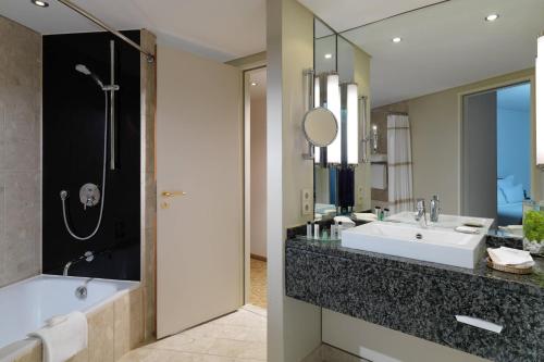 a bathroom with a tub and a sink and a mirror at Hamburg Marriott Hotel in Hamburg