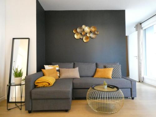a living room with a blue couch and a mirror at Clichy-Levallois Bords de Seine in Clichy