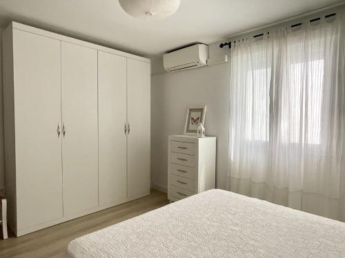 een witte slaapkamer met witte kasten en een raam bij Apartamento Ronda Centro in Ronda