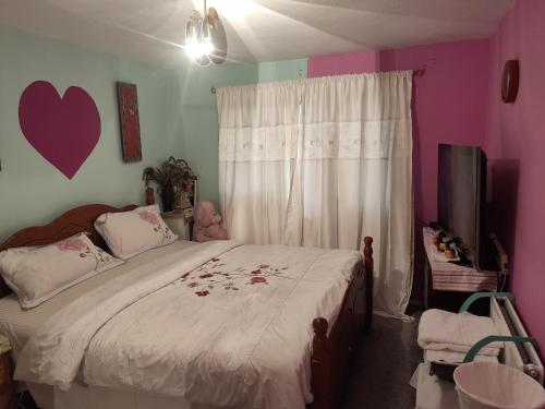 um quarto com uma cama com uma colcha branca e paredes cor-de-rosa em KEYHAVEN WALK em Manchester