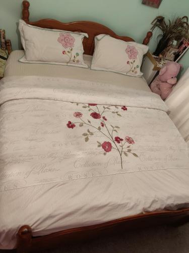 ein Bett mit einer weißen Bettdecke und rosa Blumen drauf in der Unterkunft KEYHAVEN WALK in Manchester