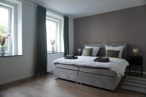 1 dormitorio con 1 cama grande y 2 ventanas en Sleepwell Apartment - Ehrensteinsuite, en Leipzig