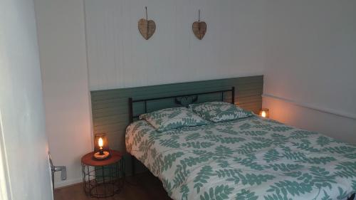 een slaapkamer met een bed met een groene sprei en twee kaarsen bij La Symphorine in Grandvilliers