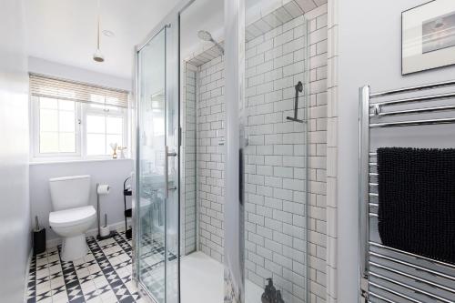 a bathroom with a toilet and a glass shower at The Kept Cottage in Hassocks