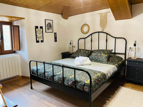ein Schlafzimmer mit einem Bett mit einem schwarzen Metallrahmen in der Unterkunft Casa Neto Goje in San Tirso de Abres