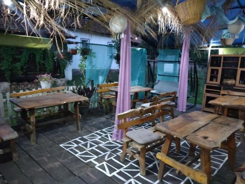 eine Terrasse mit Holztischen und Stühlen in einem Restaurant in der Unterkunft Etno selo naša avlija in Blace