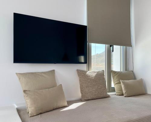Casa di Amerissa Premium Accommodation في سكيروس: غرفة معيشة مع وسائد وتلفزيون على الحائط