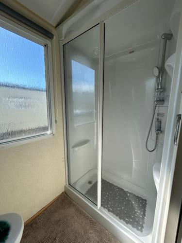 a shower in a bathroom with a window at Lyons Robin Hood Coastal Holiday Park, Savannah in Rhyl