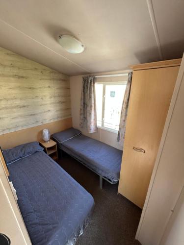 a small room with two beds and a window at Lyons Robin Hood Coastal Holiday Park, Savannah in Rhyl