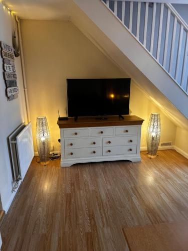 a living room with a flat screen tv on a dresser at Cosy Herne Bay Seaside Cottage in Kent