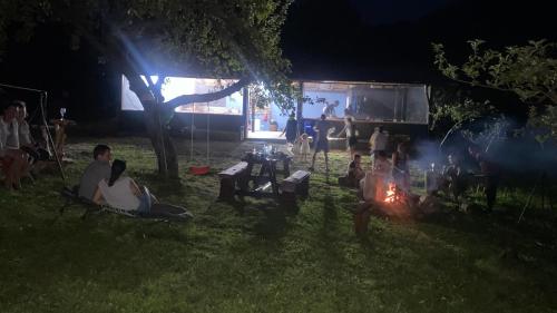 un grupo de personas sentadas alrededor de un fuego por la noche en Cumpana Camping en Băile Olăneşti