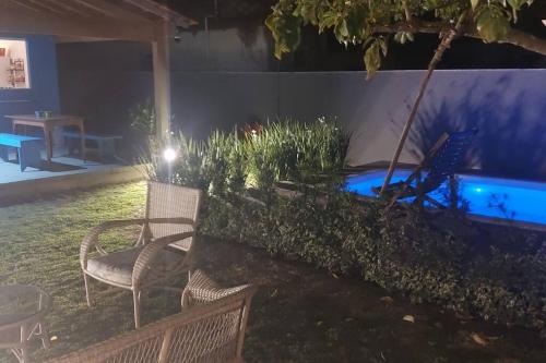 a patio with chairs and a swimming pool at night at CASA TROPICANA - ITAÚNAS Centro in Itaúnas