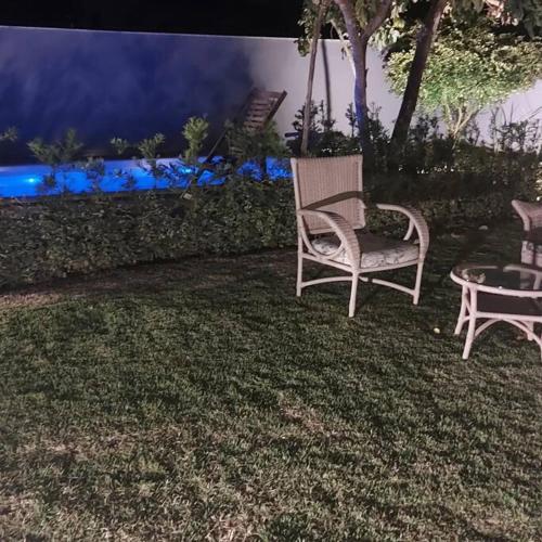 two chairs and a table in a yard at night at CASA TROPICANA - ITAÚNAS Centro in Itaúnas