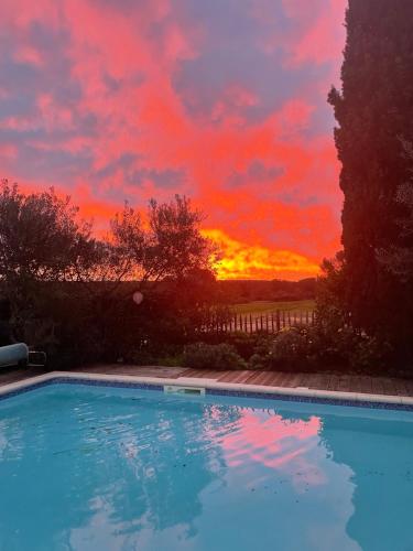 - un coucher de soleil au-dessus d'une piscine dans une cour dans l'établissement Grande maison à teyran (34), à Teyran