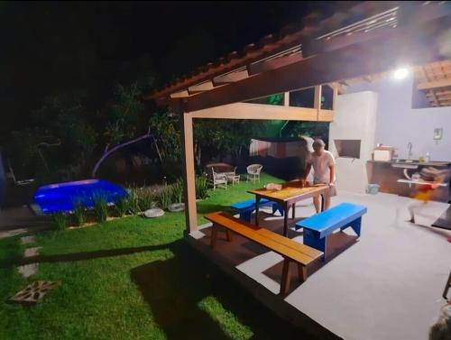 a man sitting at a table in a backyard at night at CASA TROPICANA - ITAÚNAS Centro in Itaúnas