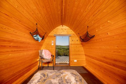 ein Schlafzimmer in einem Blockhaus mit einem Bett und einem Fenster in der Unterkunft Ty Grug Pods in Bryngwyn