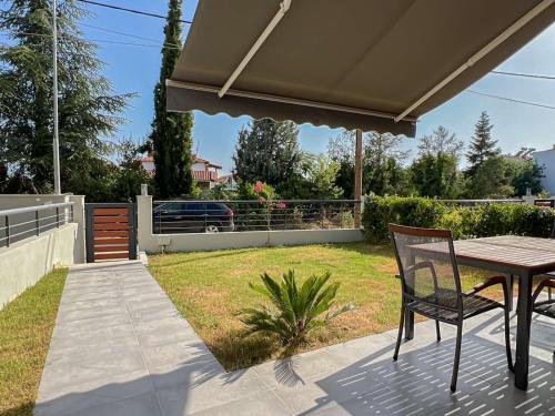 een patio met een tafel en stoelen in een tuin bij Kalisti Relax Villa in Nikiti