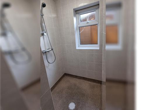 een douche met een glazen deur en een raam bij Spacious Flat Near Rochdale Centre Self Check-in Free Parking & Fast Wi-Fi in Rochdale