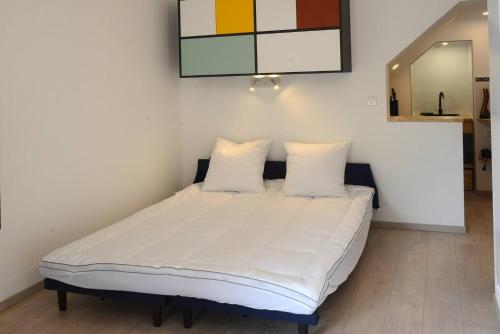 1 cama con sábanas blancas y almohadas en una habitación en Le 38 derrière l'église, en Clairvaux-les-Lacs
