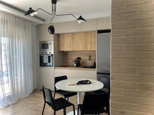 a kitchen with a white table and black chairs at C&C3 Apartments in Alexandroupoli