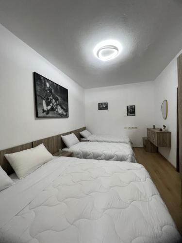 Duas camas num quarto com uma grande cama branca em Your Joyful Spot em Shkodër