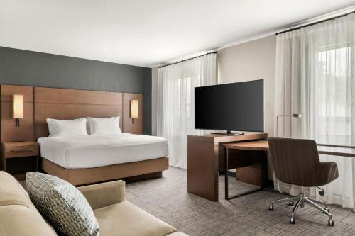 Una habitación de hotel con una cama y un escritorio con televisión. en Residence Inn by Marriott Laval, en Laval
