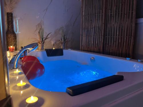 uma casa de banho com uma banheira azul com velas em LE BALI SPA em Hardricourt