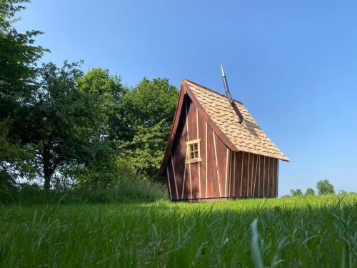 eine rote Scheune auf einem Feld mit hoher Wiese in der Unterkunft LES INSOLITES DE SOPHIE 