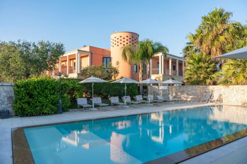 a swimming pool with chairs and umbrellas next to a building at Villa Rosa Antico Dimora Storica in Otranto