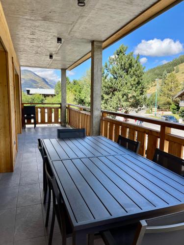 d'une grande table en bois sur un balcon avec vue. dans l'établissement Appartement les Clochettes 1 - Pied des pistes, à Les Deux Alpes