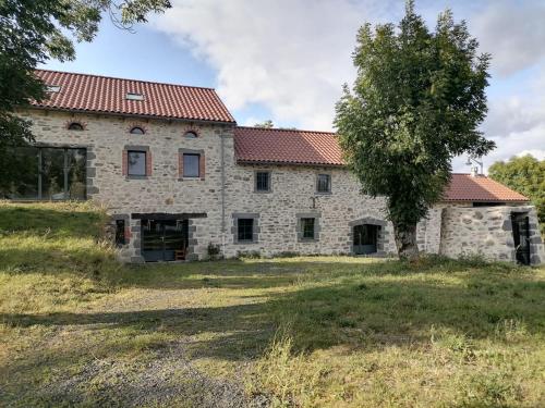 ein altes Steinhaus mit einem Baum davor in der Unterkunft Relais des Gorges de la Truyère in Anglards-de-Saint-Flour