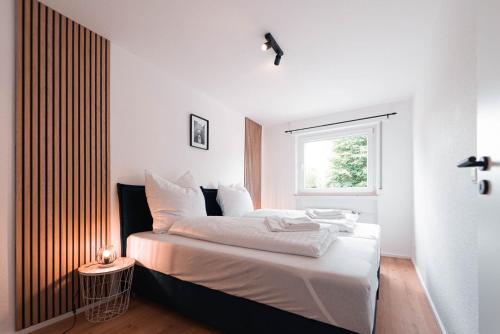 Schlafzimmer mit einem Bett mit weißer Bettwäsche und einem Fenster in der Unterkunft unique Komfortsuite - Göppingen in Göppingen