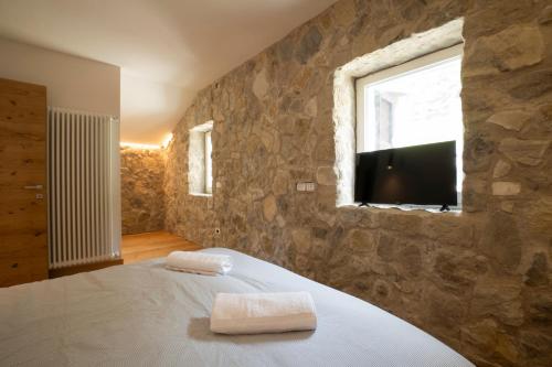 una camera da letto con un muro in pietra, un letto e una TV di SnowLake Suite & Apartment ad Alleghe