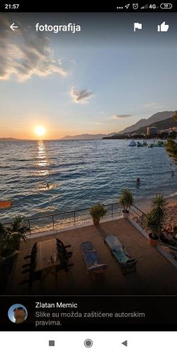 a view of a beach with the sun setting over the water at Beach rooms Riviera - Žuta Kuća in Makarska