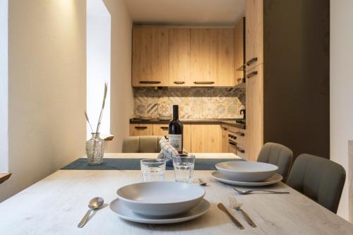 a table with two white plates and a bottle of wine at SnowLake Suite & Apartment in Alleghe