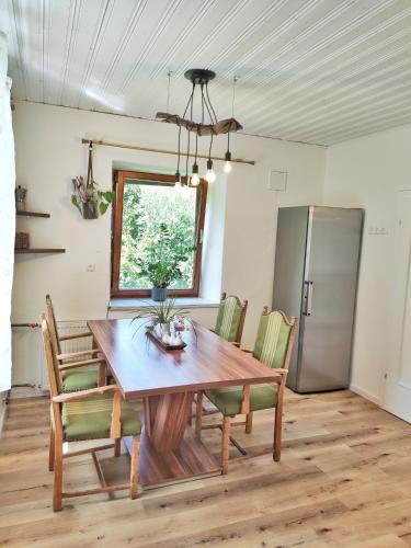 a dining room table with chairs and a refrigerator at Appartments am Waldbad - Unterm Nussbaum in Rassing