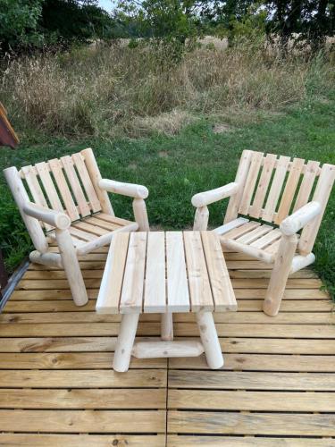 zwei Holzstühle und ein Picknicktisch auf einer Terrasse in der Unterkunft LES INSOLITES DE SOPHIE 