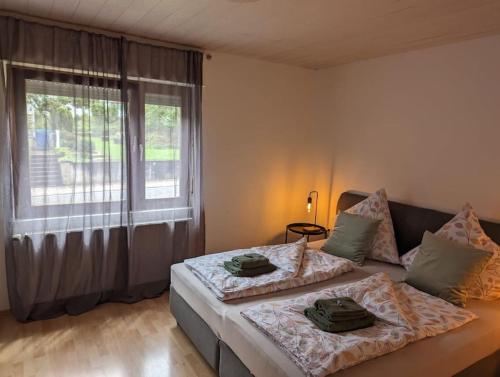 a bedroom with two beds and a large window at Heufelsen Ferienwohnung in Hinterweidenthal