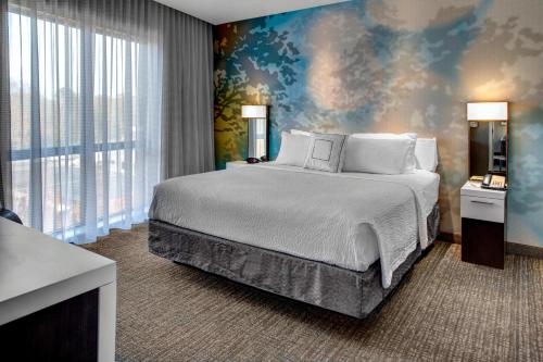 een slaapkamer met een groot bed en een muurschildering bij Courtyard by Marriott Carrollton in Carrollton